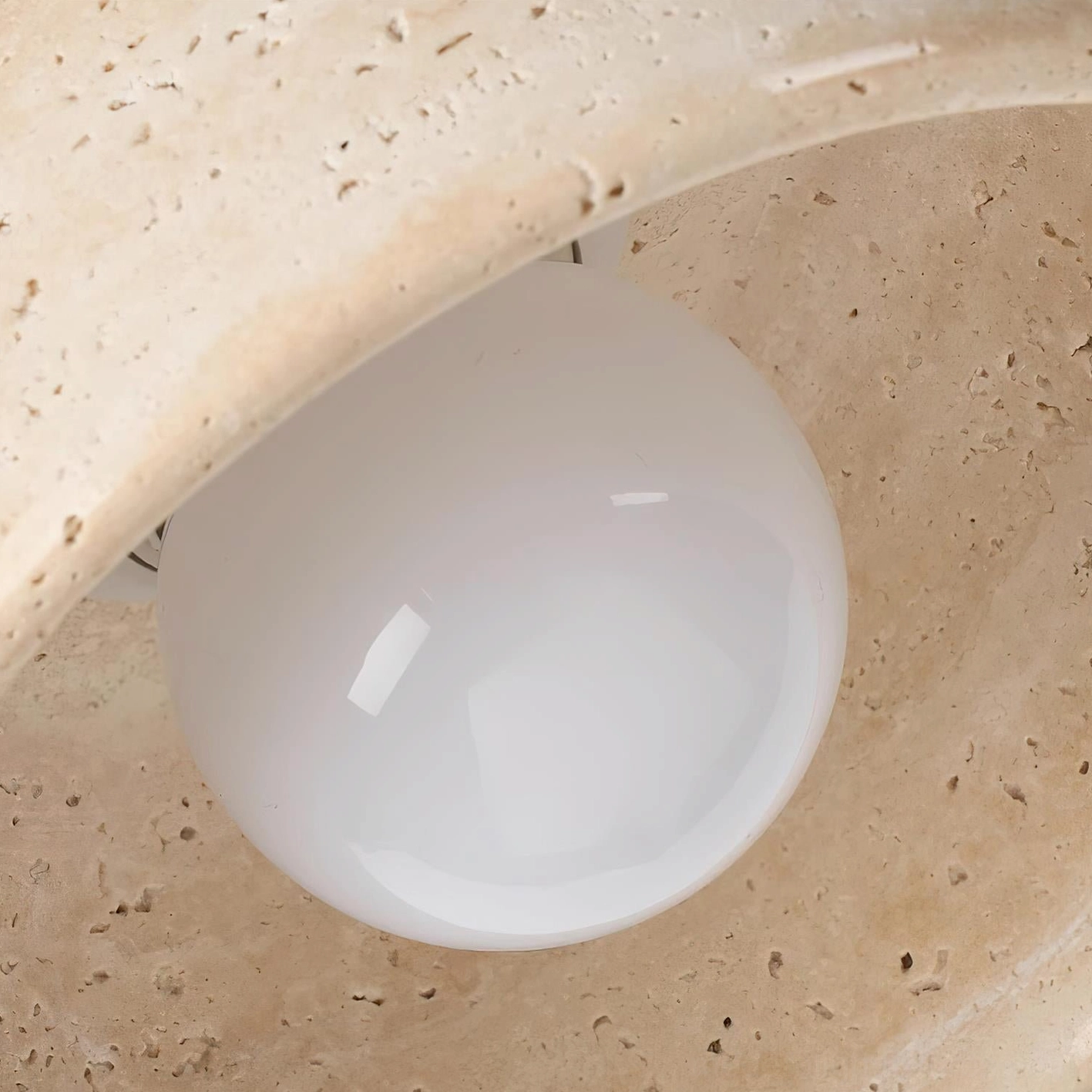 Modern travertine stone pendant light with diffused ambient illumination through porous natural stone material