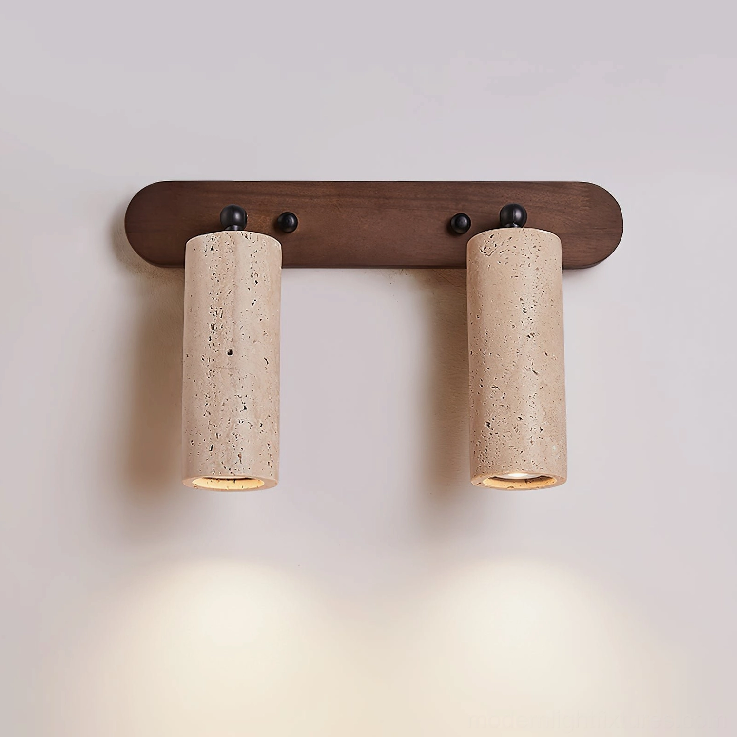 Ricerca travertine wall sconce softly illuminating bathroom mirror space with warm downlight glow