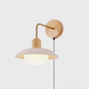 Travertine plug-in wall sconce with brushed brass arm and wooden mount, front studio view showing speckled stone shade and modern design