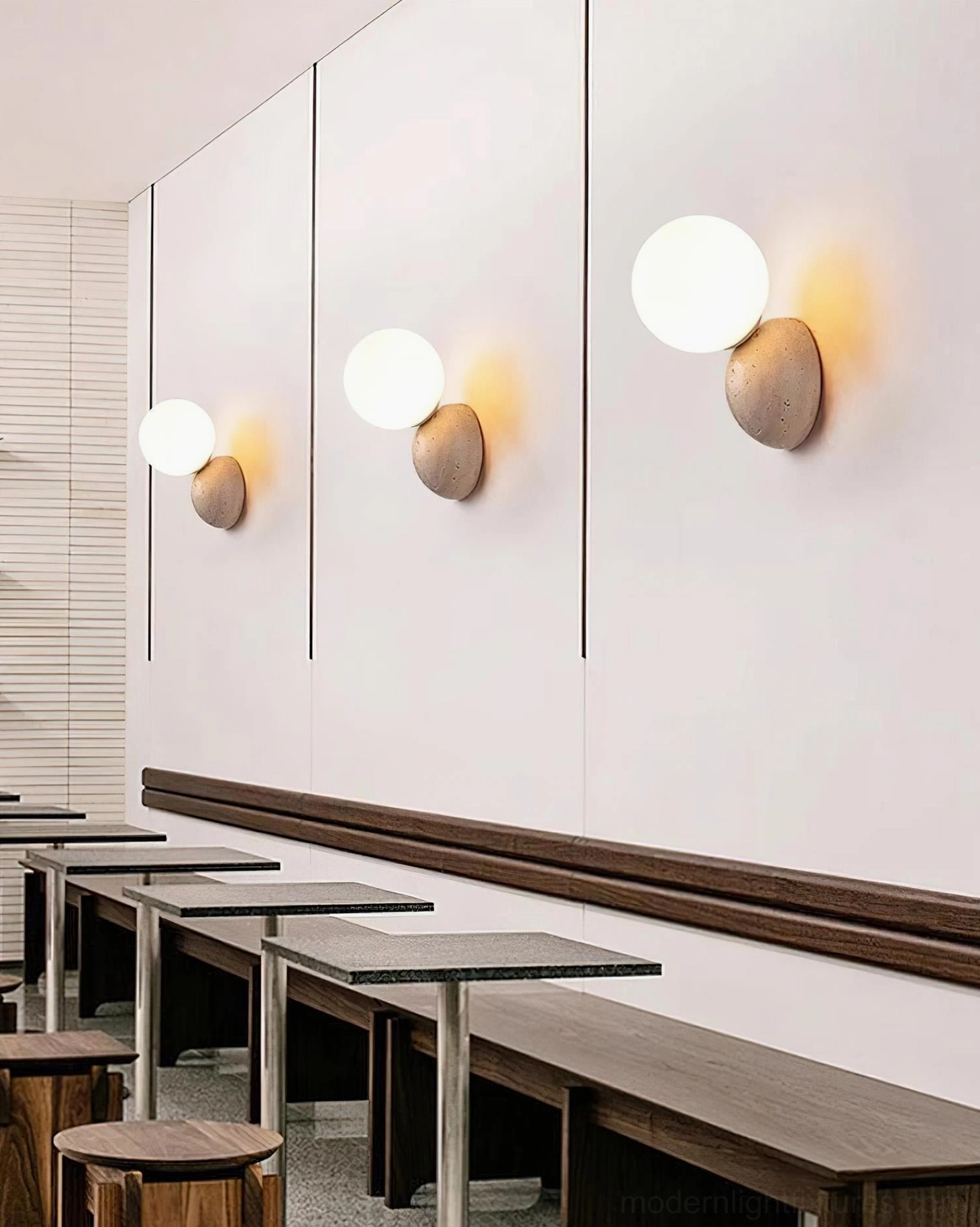 Multiple travertine wall lamps creating accent lighting along commercial cafe hallway, dramatic effect