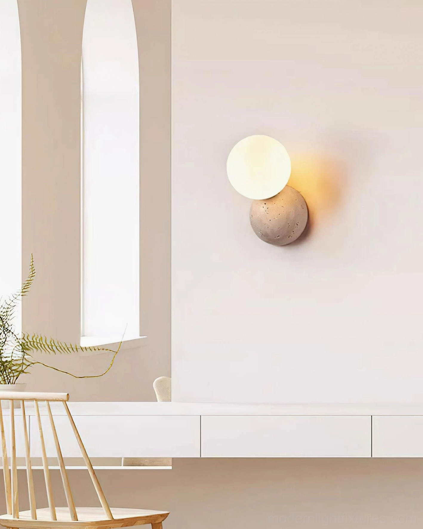 Compact travertine wall lamp mounted on residential wall above dining nook, natural stone minimalist aesthetic
