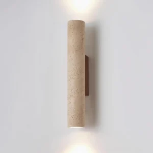 Lit travertine wall sconce with warm upward and downward light, showcasing porous stone texture and natural grain