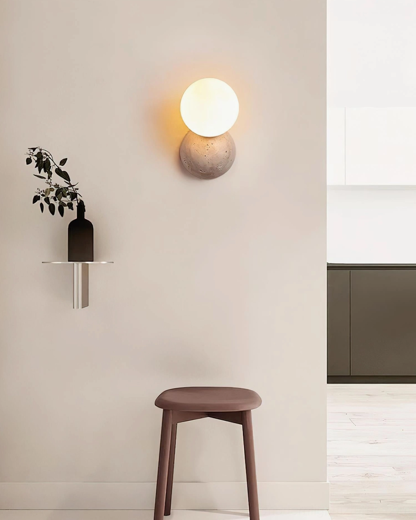 Single travertine wall sconce in minimalist home corner with wooden stool and wall shelf, warm neutral decor