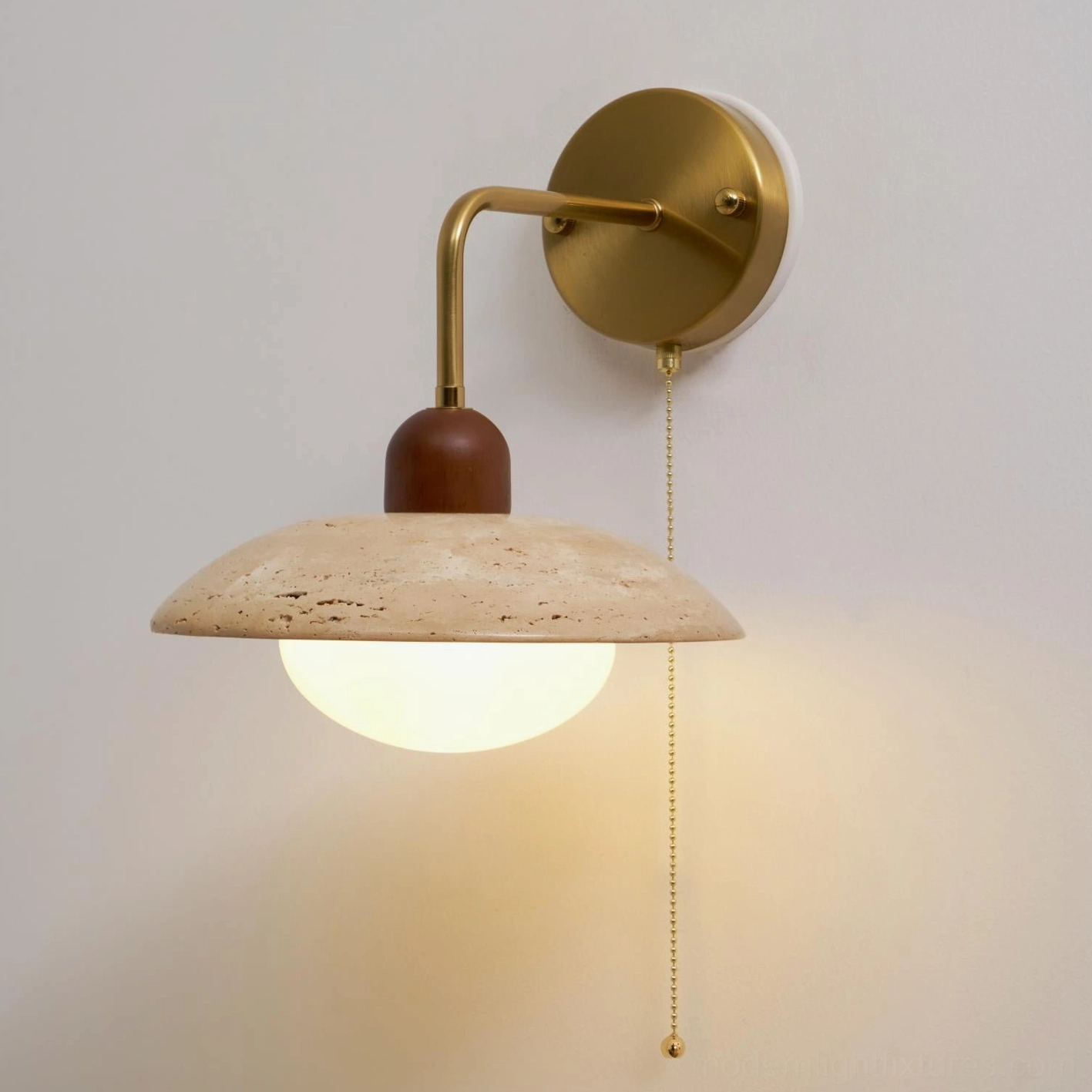 Travertine wall sconce three-quarter angle showing illuminated warm glow and curved brass arm design