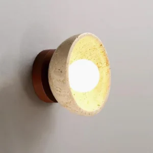 Side profile of travertine stone wall sconce showing slanted shade and wooden mounting base against gray wall