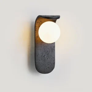 Contemporary wall sconce three-quarter angle showing curved travertine base with matte finish and soft studio shadow detail