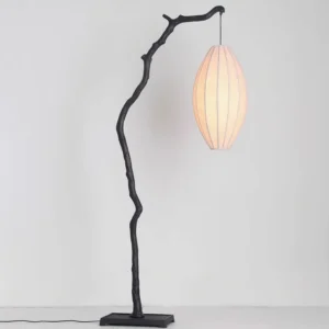 Minimalist tree branch floor lamp with twisted metal stand and warm beige fabric shade on white backdrop