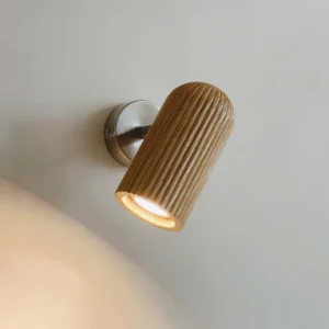 Trevio modern wall lamp side close-up showing light brown striped wood shade with warm LED lighting and brushed metal arm
