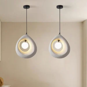 Two matching Tricia minimalist pendant lights suspended in contemporary beige interior with black cords, creating warm ambient lighting for modern home design