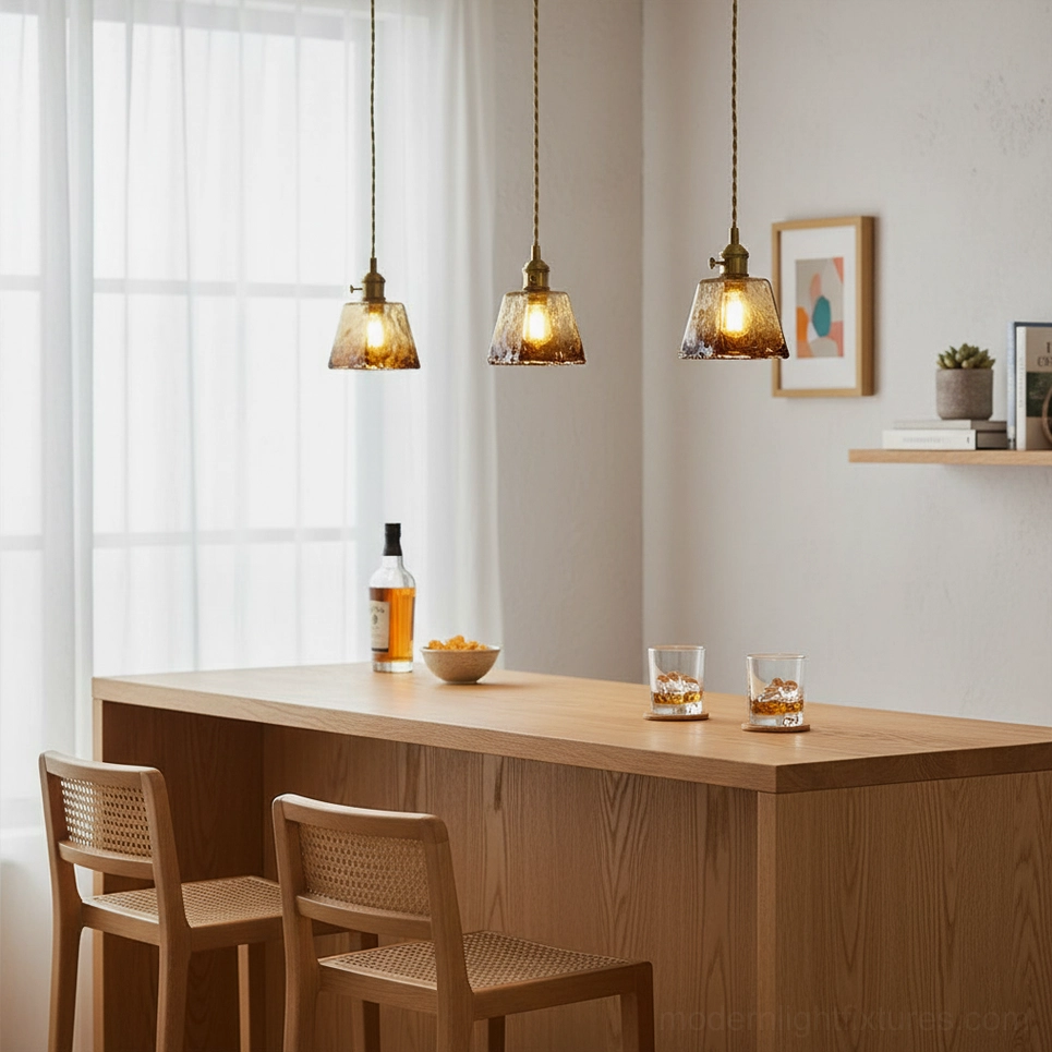 Triple vintage brass amber pendant lights over kitchen bar - warm Japandi aesthetic