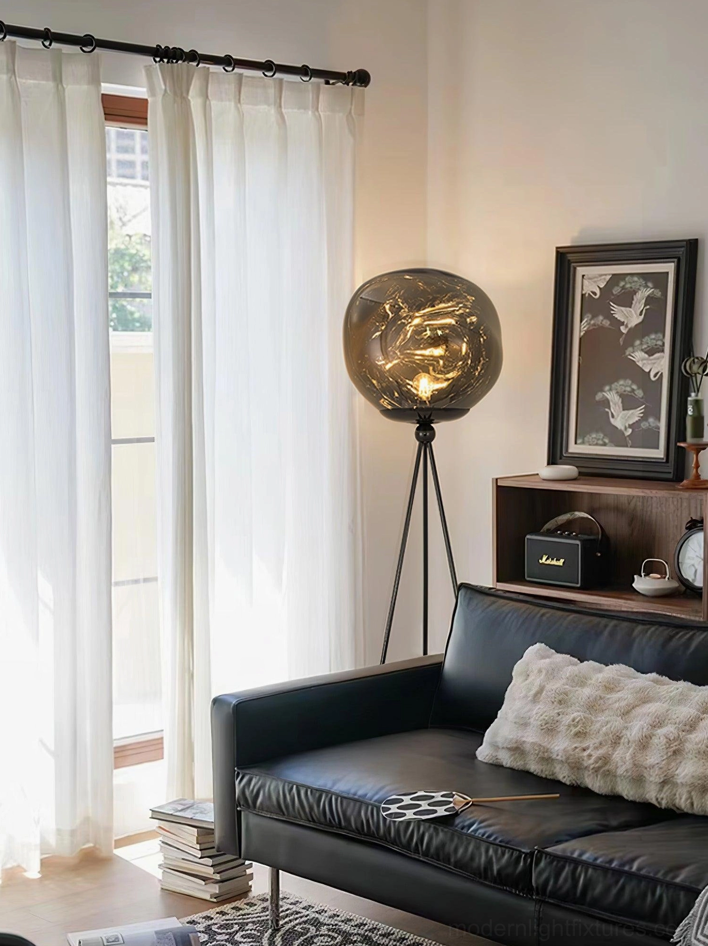 Contemporary black tripod floor lamp with molten glass shade in dark leather sofa living room rear angle view