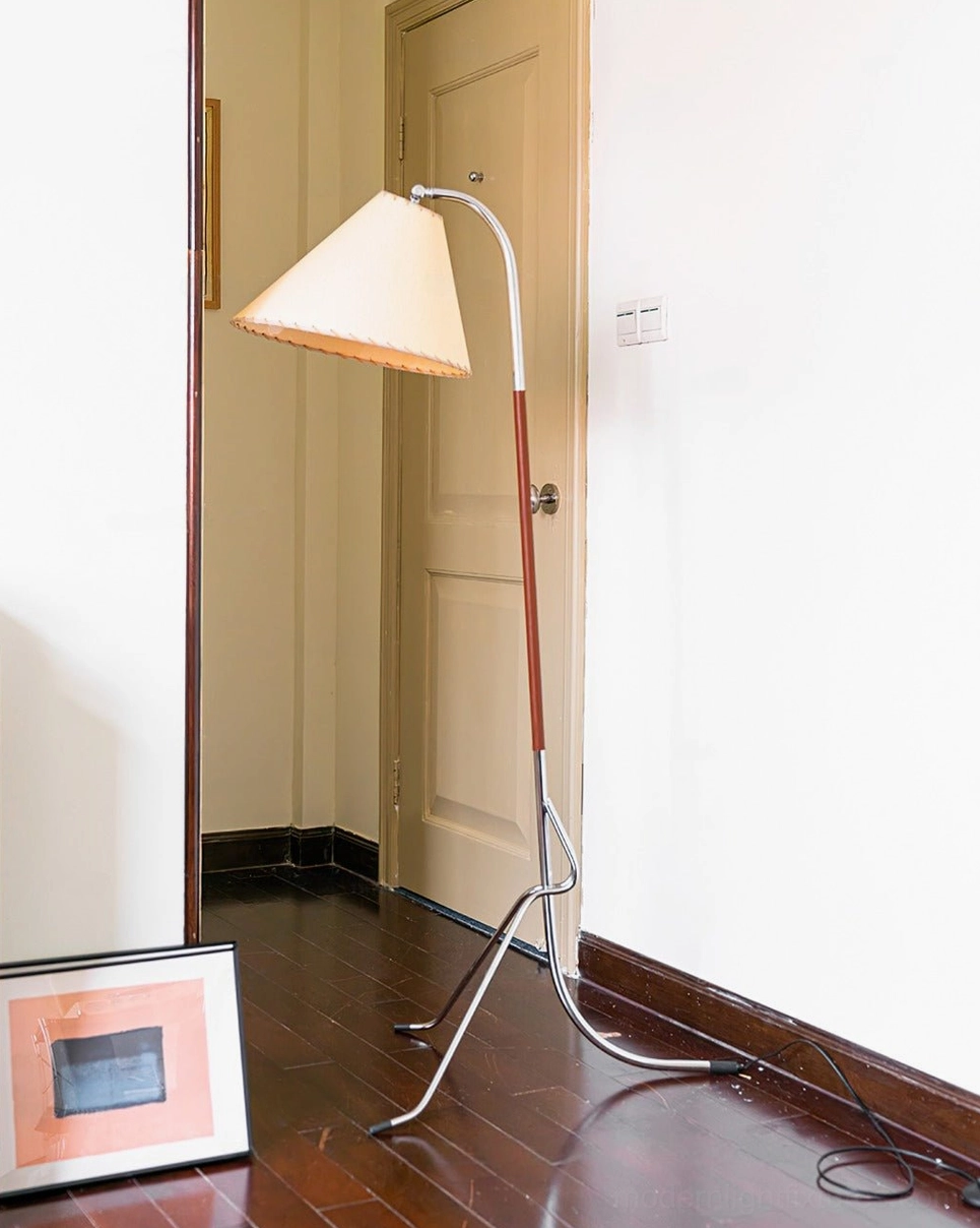 Tripod floor lamp in residential entryway with hardwood flooring, positioned in narrow corner space with framed wall art nearby, space-saving design
