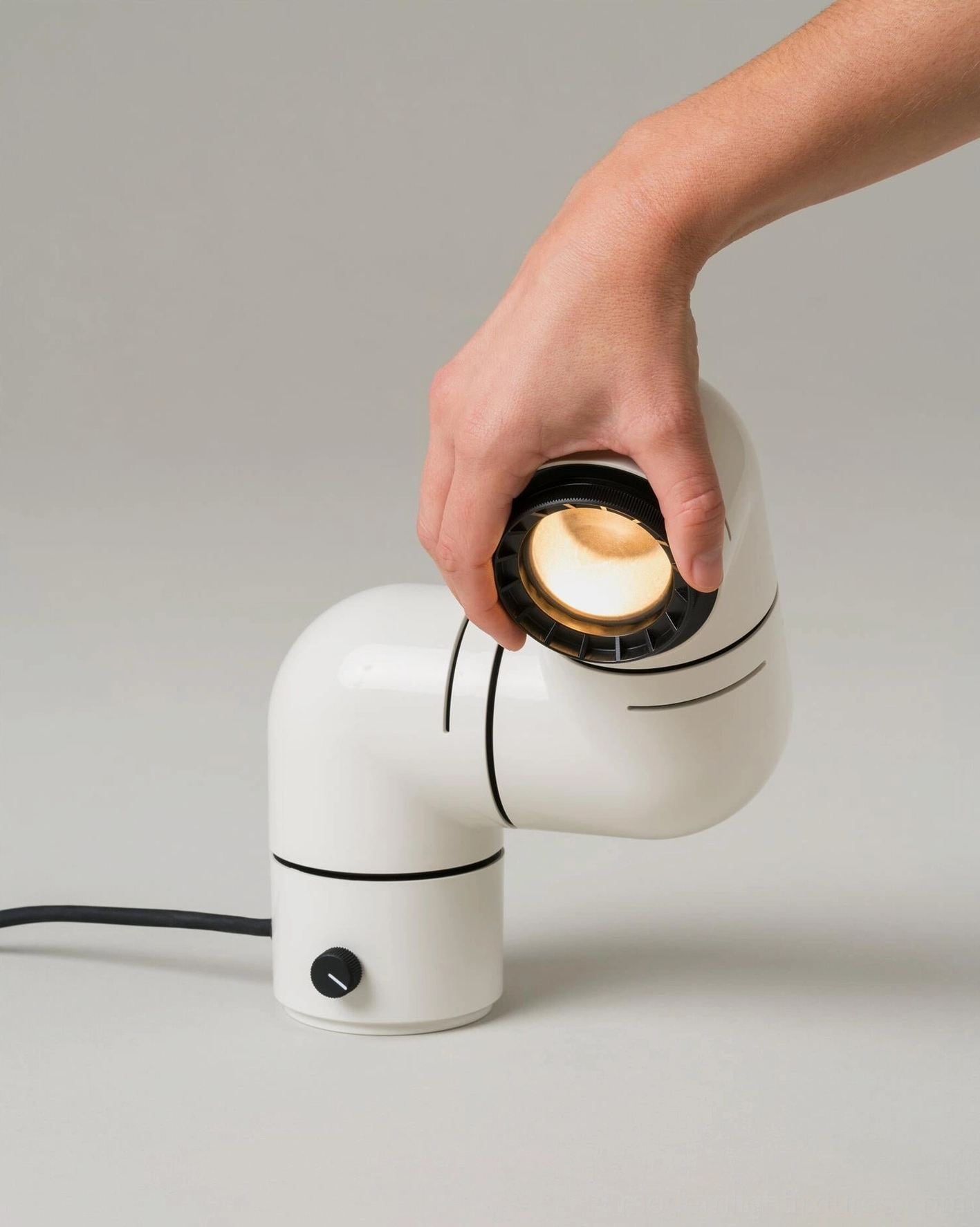 Tubular table lamp close-up hand adjusting lamp head with visible illuminated LED