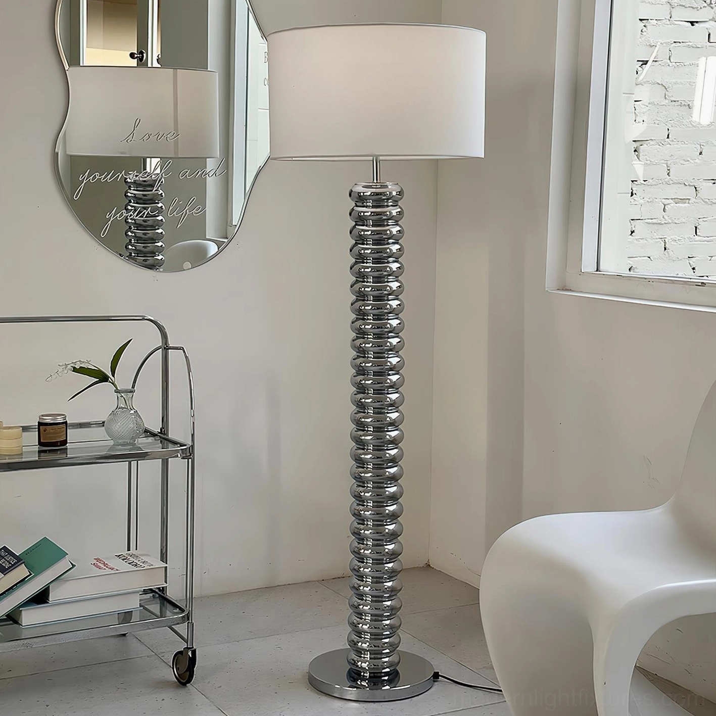 Chrome polished metal Tula Twist floor lamp in contemporary living room setting with mirror and metal trolley, three-quarter angle view