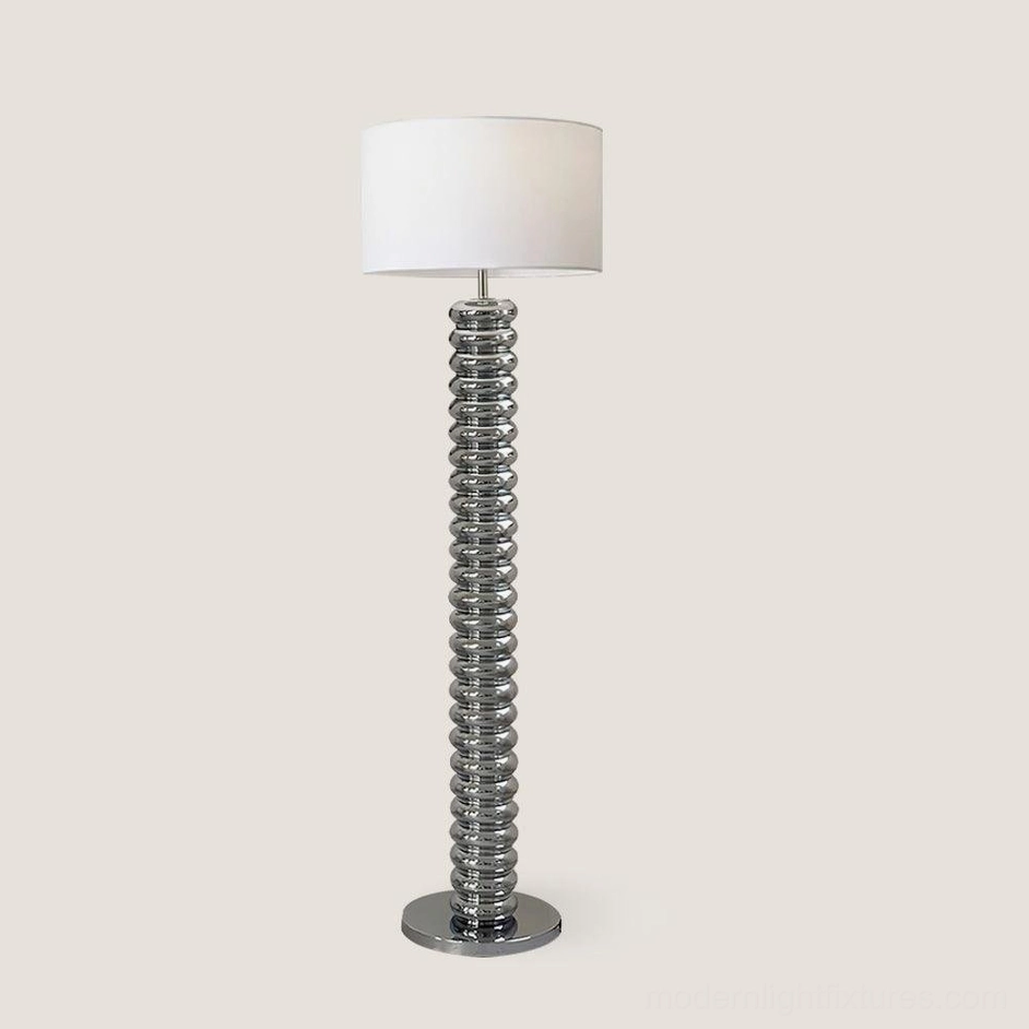 Chrome silver Tula Twist floor lamp with polished metal ribbed pole and white fabric shade, professional product photograph