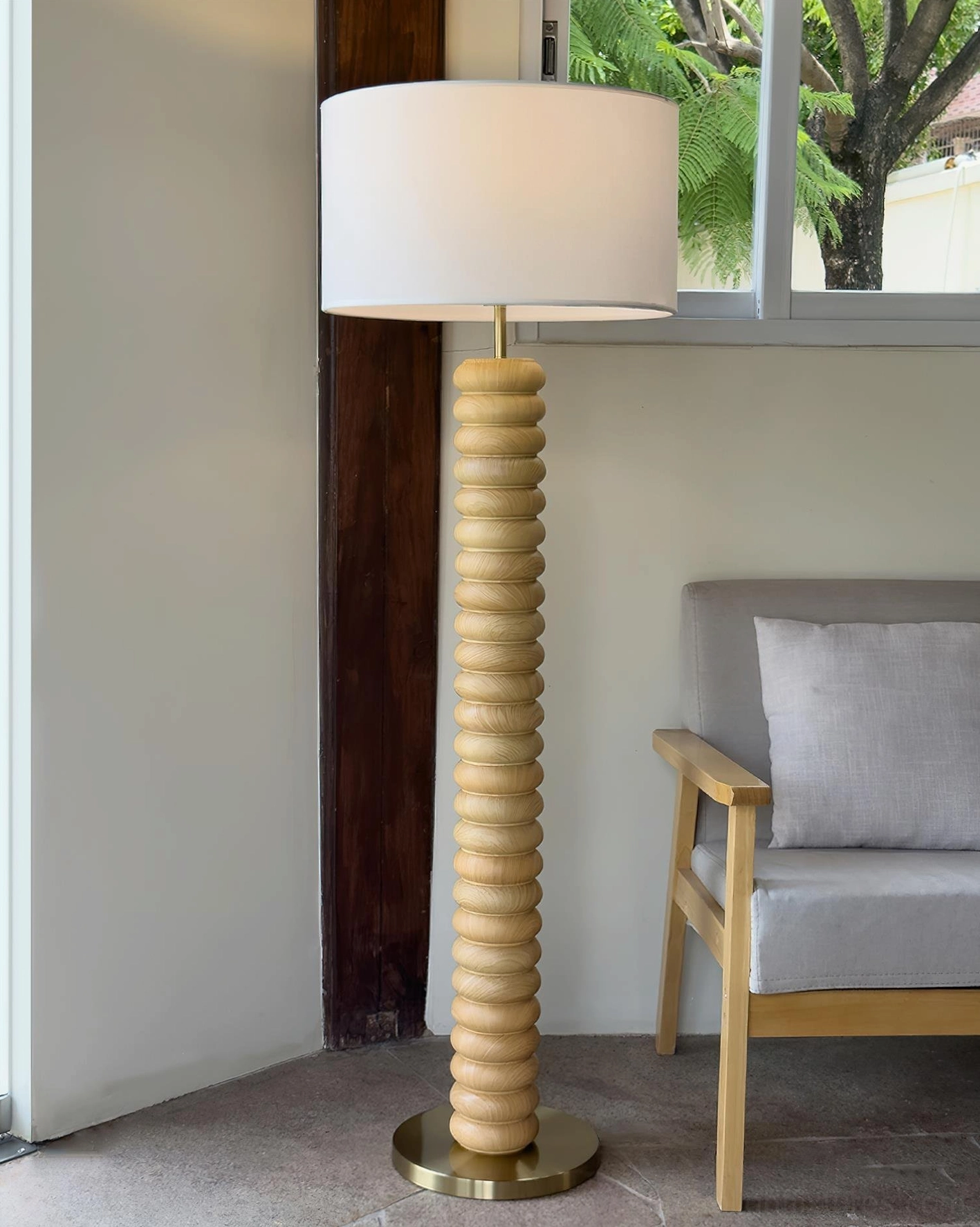 Natural light wood ribbed pole modern floor lamp with brass base in bright residential living room with wooden furniture