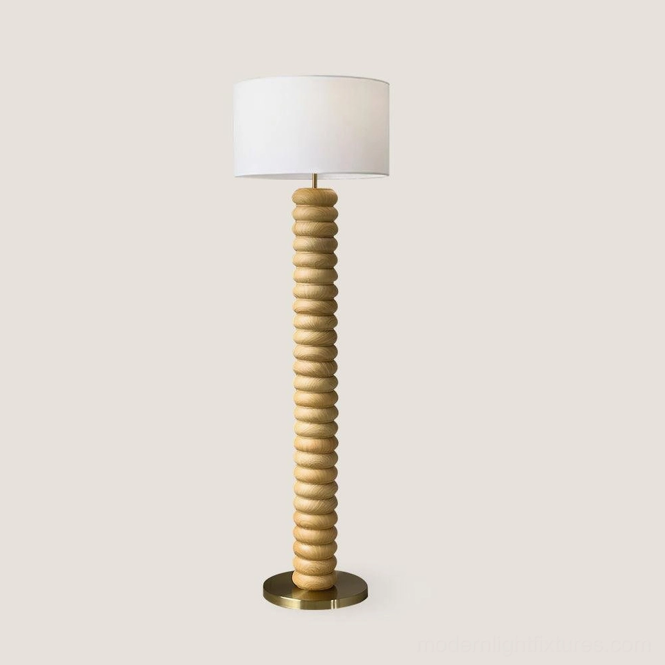 Natural wood tone Tula Twist modern floor lamp with brass base and ivory fabric drum shade, studio display