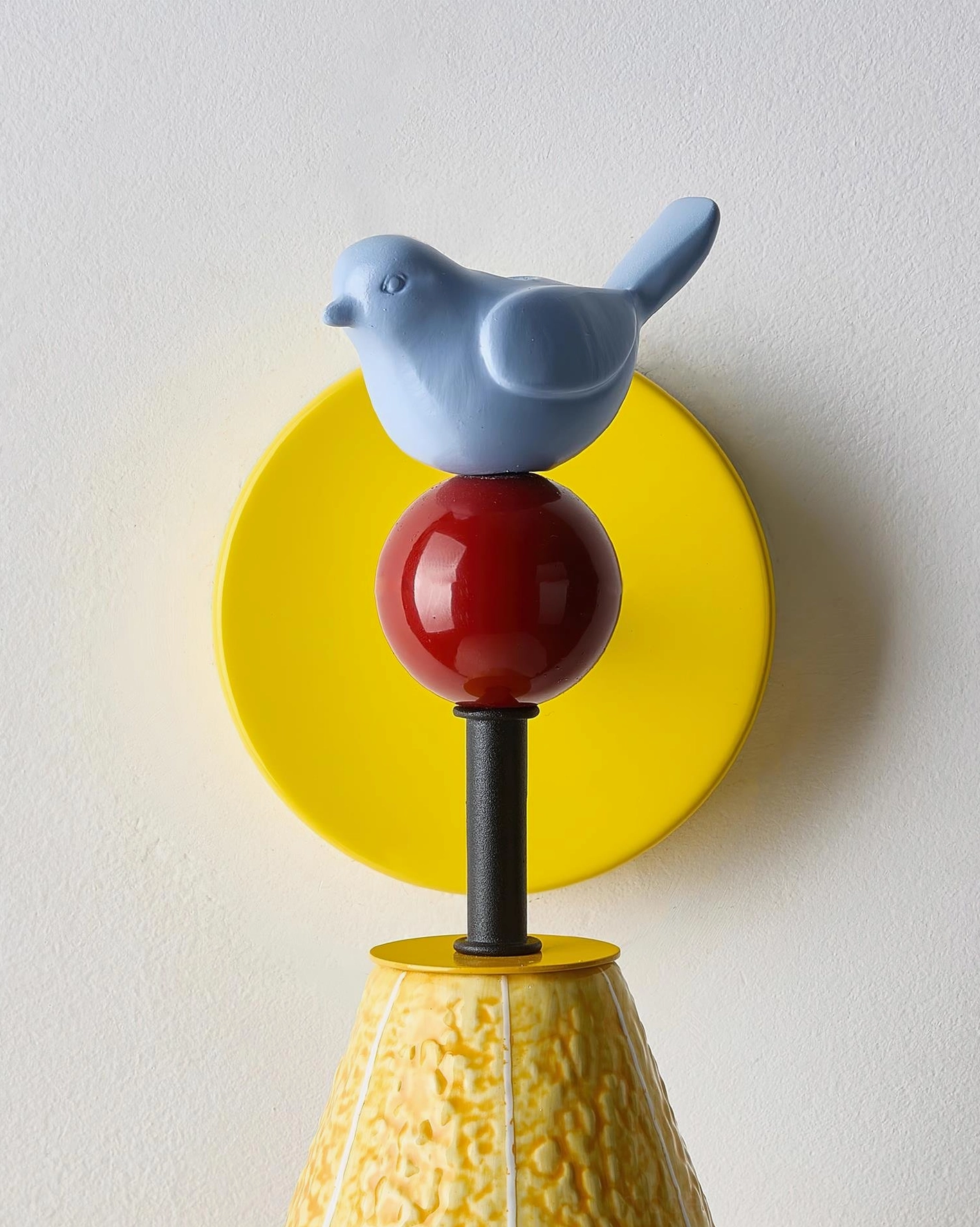 Modern playful bird-themed wall sconce with yellow textured shade casting decorative light, contemporary design