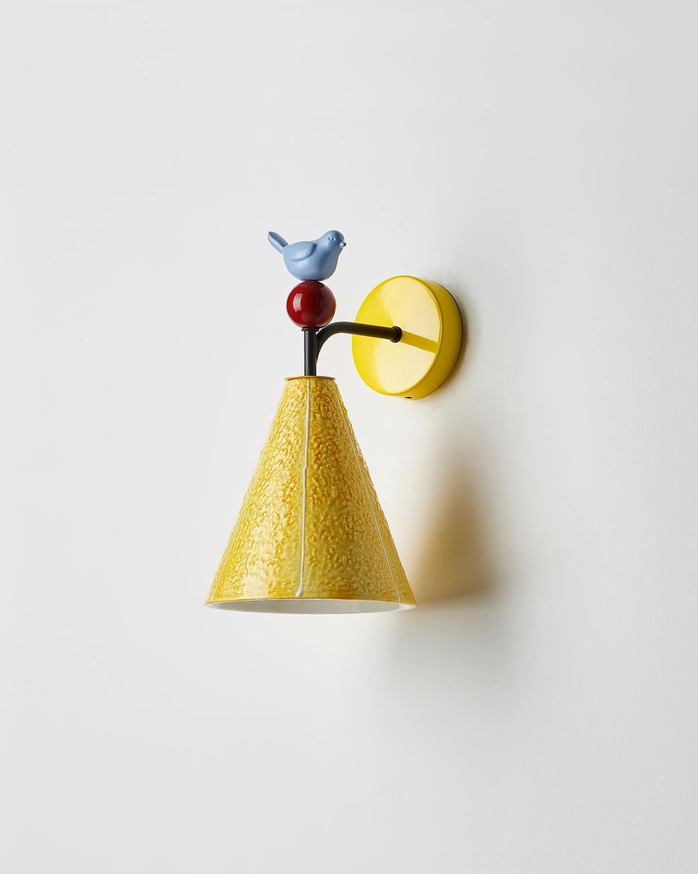 Compact yellow ceramic bird wall sconce with textured conical lampshade, front flat angle on neutral background