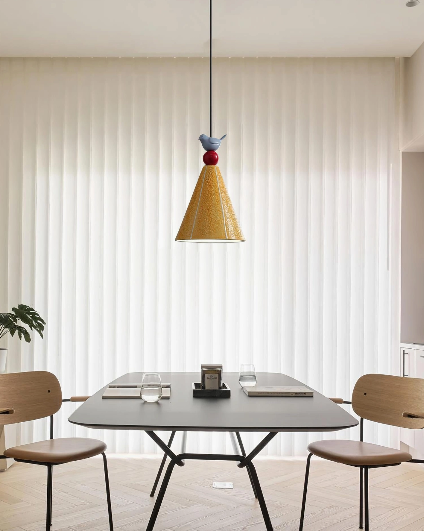 Ceramic cone pendant light with bird finial above long dining table, sheer curtains backdrop, contemporary home lighting