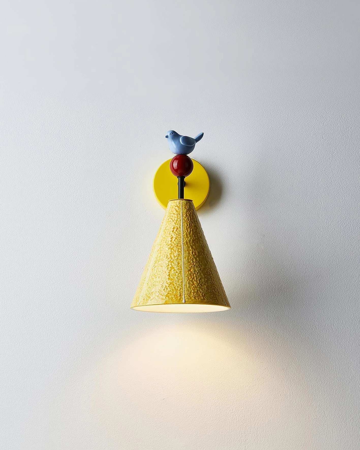 Tweetie bird wall sconce with textured yellow shade creating ambient warm light pool below fixture