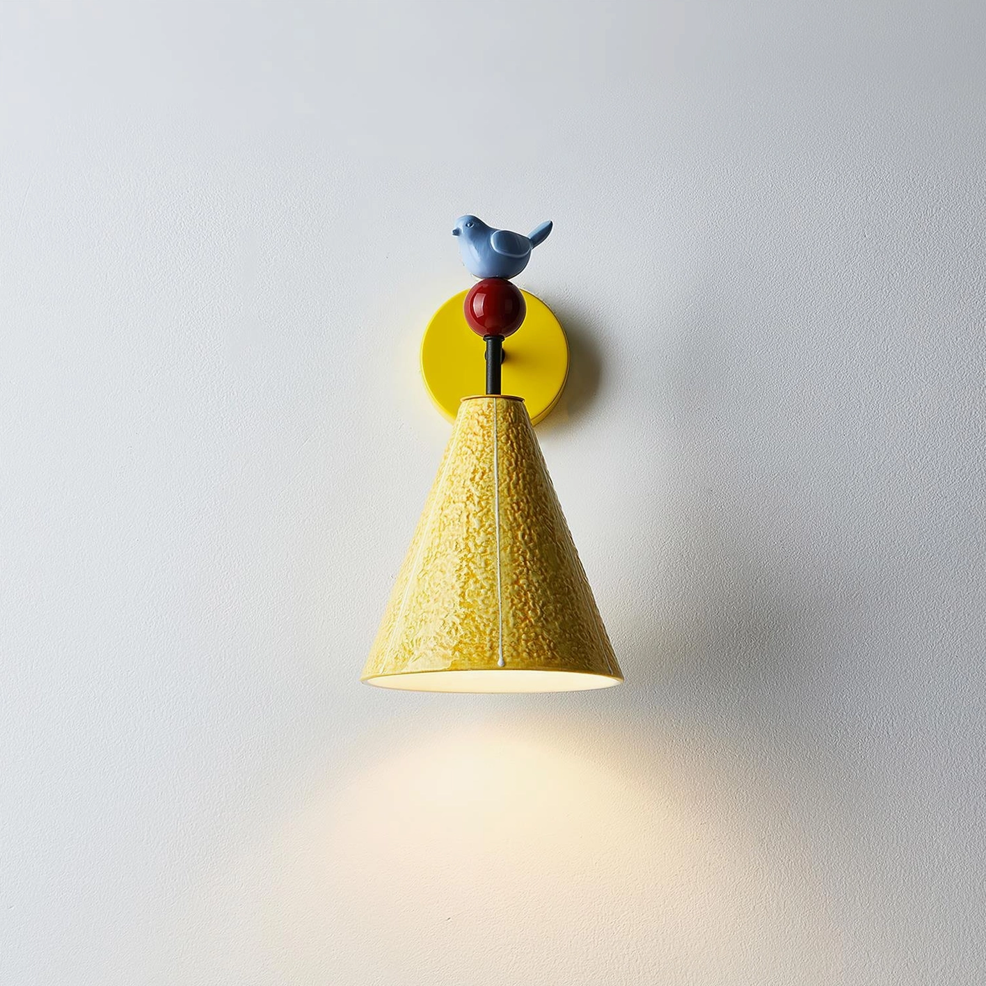 Ceramic bird wall lamp casting warm downlight spot on wall, minimalist playful design detail visible