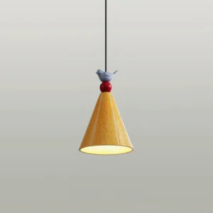 Yellow ceramic pendant lamp with red sphere and blue bird ornament, lit interior view, studio photography with gray background