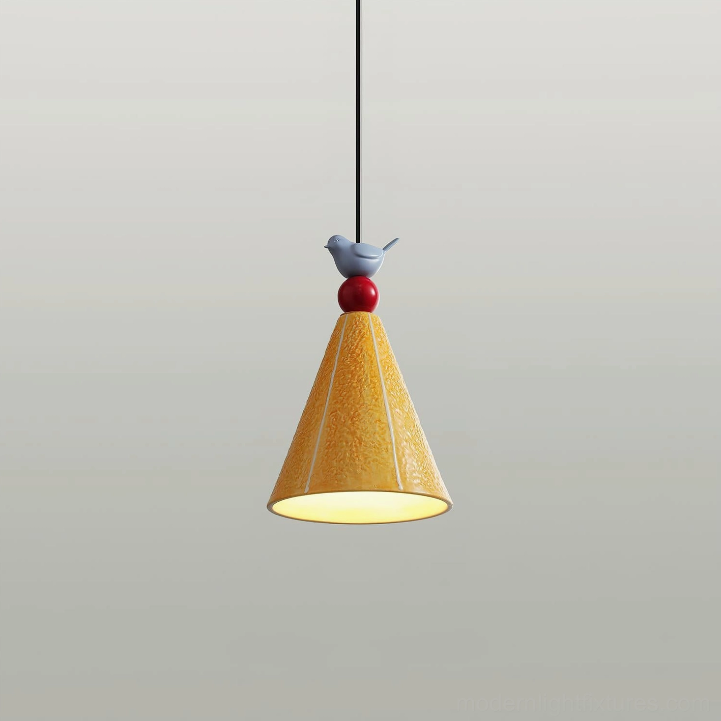 Yellow ceramic pendant lamp with red sphere and blue bird ornament, lit interior view, studio photography with gray background