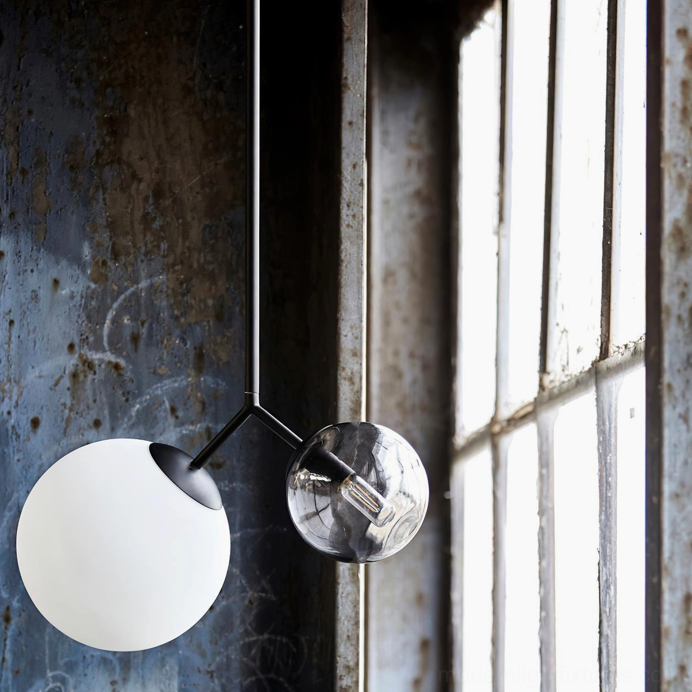 Twis pendant lamp with black metal rod and asymmetrical frosted glass globes shown from side angle in industrial setting