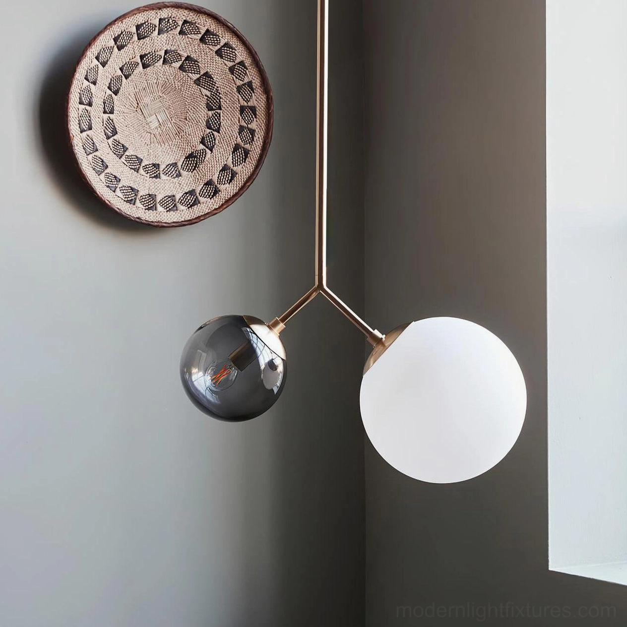 Twis pendant fixture with brass metal parts and mixed frosted white and smoke gray glass globes in corner installation