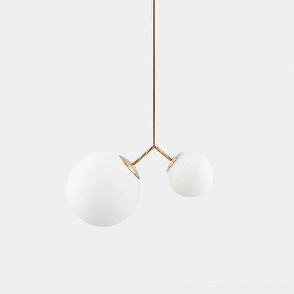 Twis contemporary pendant light with brass metal rod and frosted white glass globes in modern living space