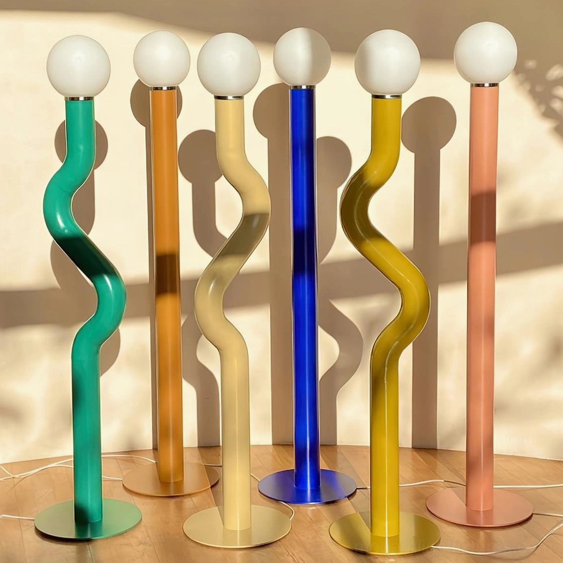 Six Twistie floor lamp color options with twisted metal bases viewed from above in sunlit studio space