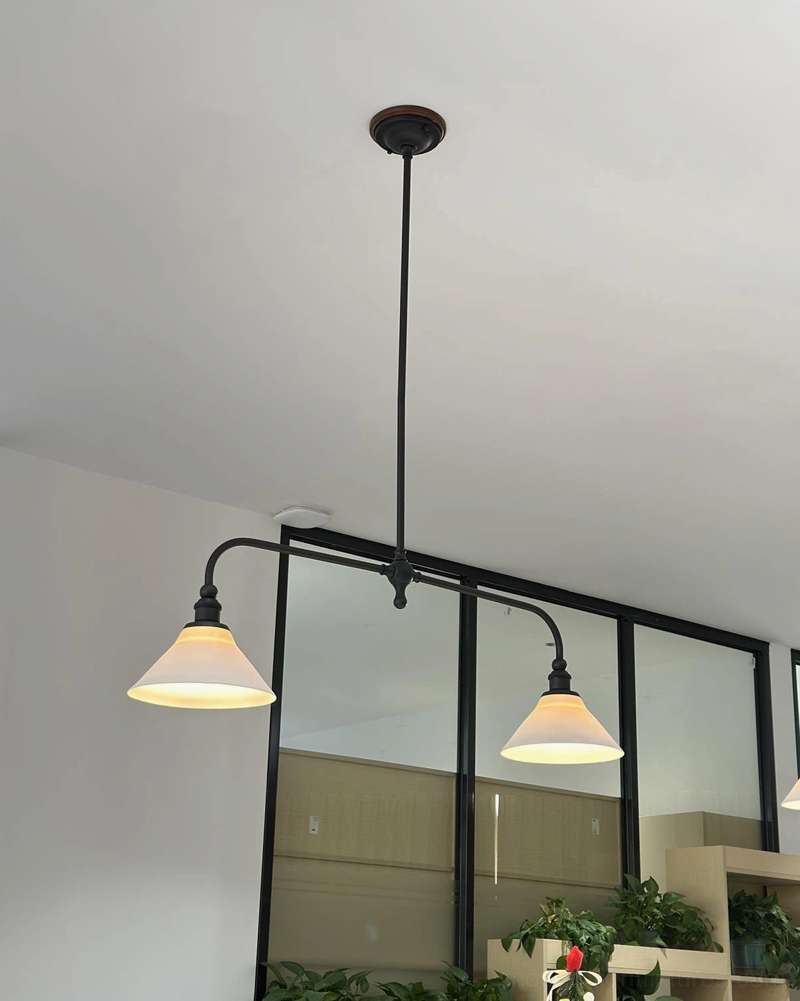 Two-light brass linear pendant chandelier with opal ceramic shades ideal for mid-century modern interior design schemes