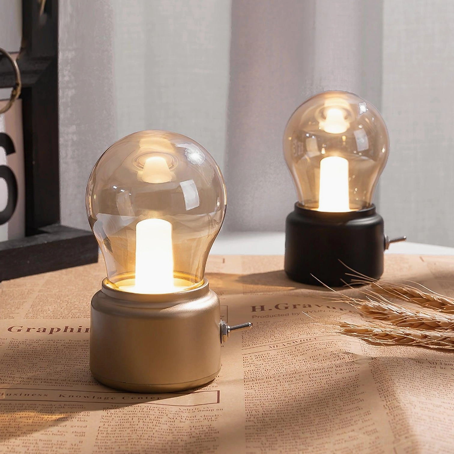 Pair of decorative mini table lamps in gold and black finishes on desk with wheat prop accents