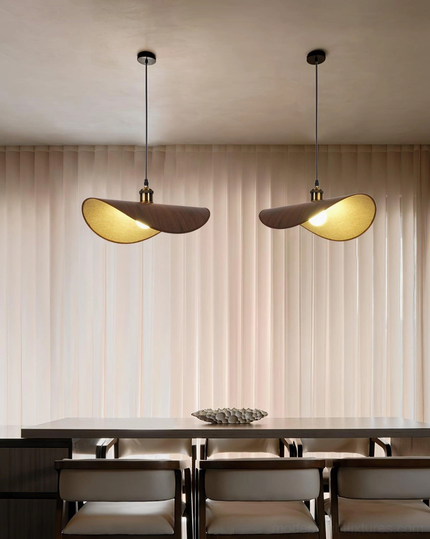 Pair of handcrafted wabi-sabi pendant lights above dining table with sheer curtains and neutral interior styling
