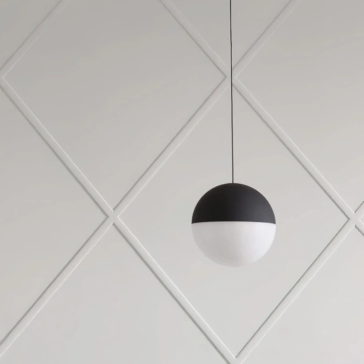 Two-tone spherical pendant light with black upper hemisphere and white lower hemisphere, minimalist Nordic design studio view