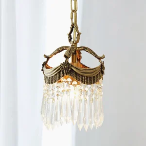 Illuminated Vacarro crystal pendant chandelier with warm glow and decorative fabric trim - close-up