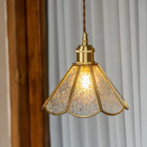 Lit Valeria pendant light fixture illuminated over window, vintage brass and embossed glass warm lighting