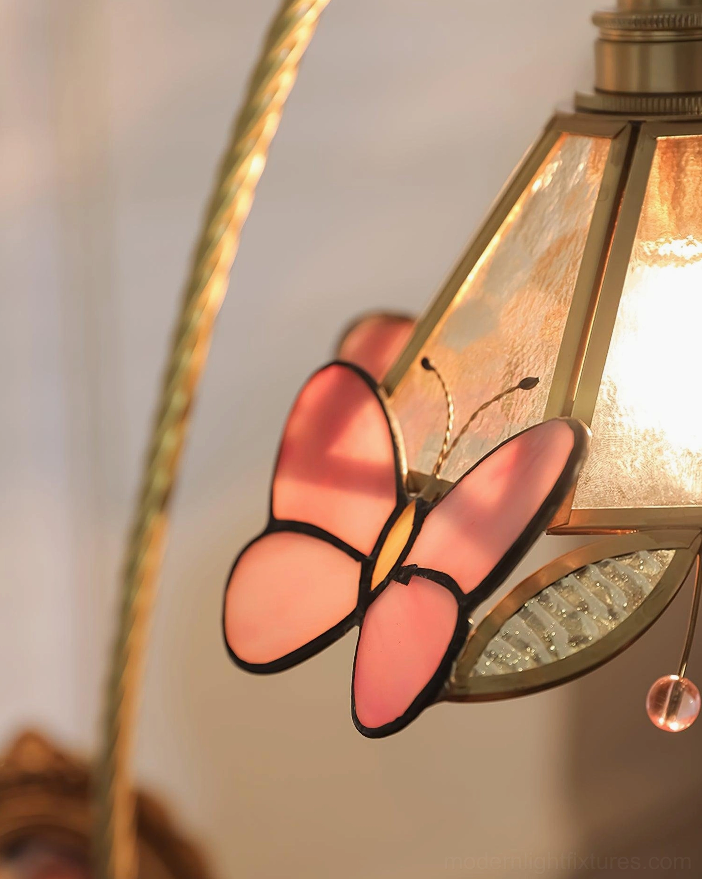 Three-quarter angle of Valerie Butterfly decorative table lamp showing brass arm curve and walnut wood base construction detail