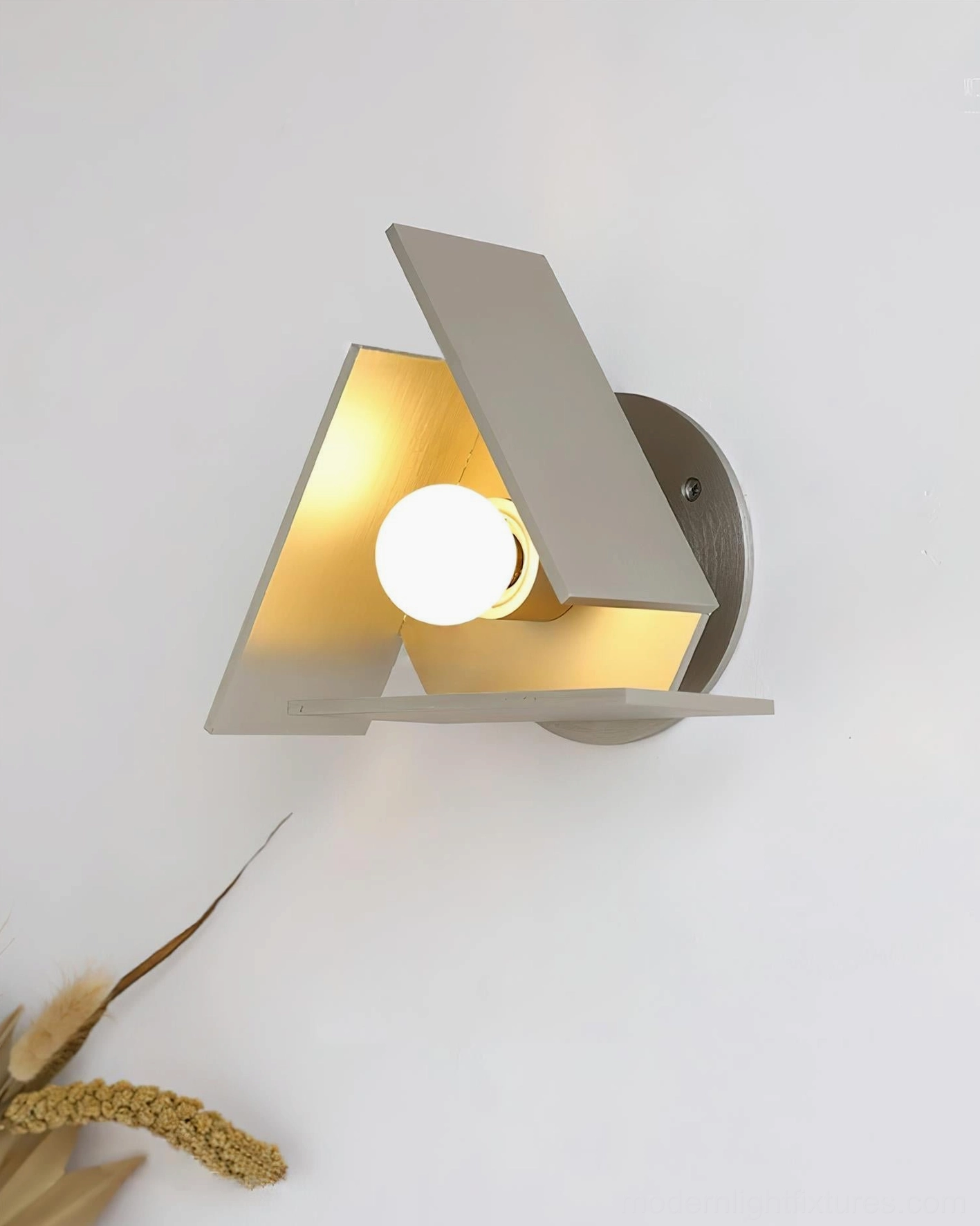 Vanta wall sconce front overhead angle with exposed white globe bulb glowing warm interior and dried wheat backdrop