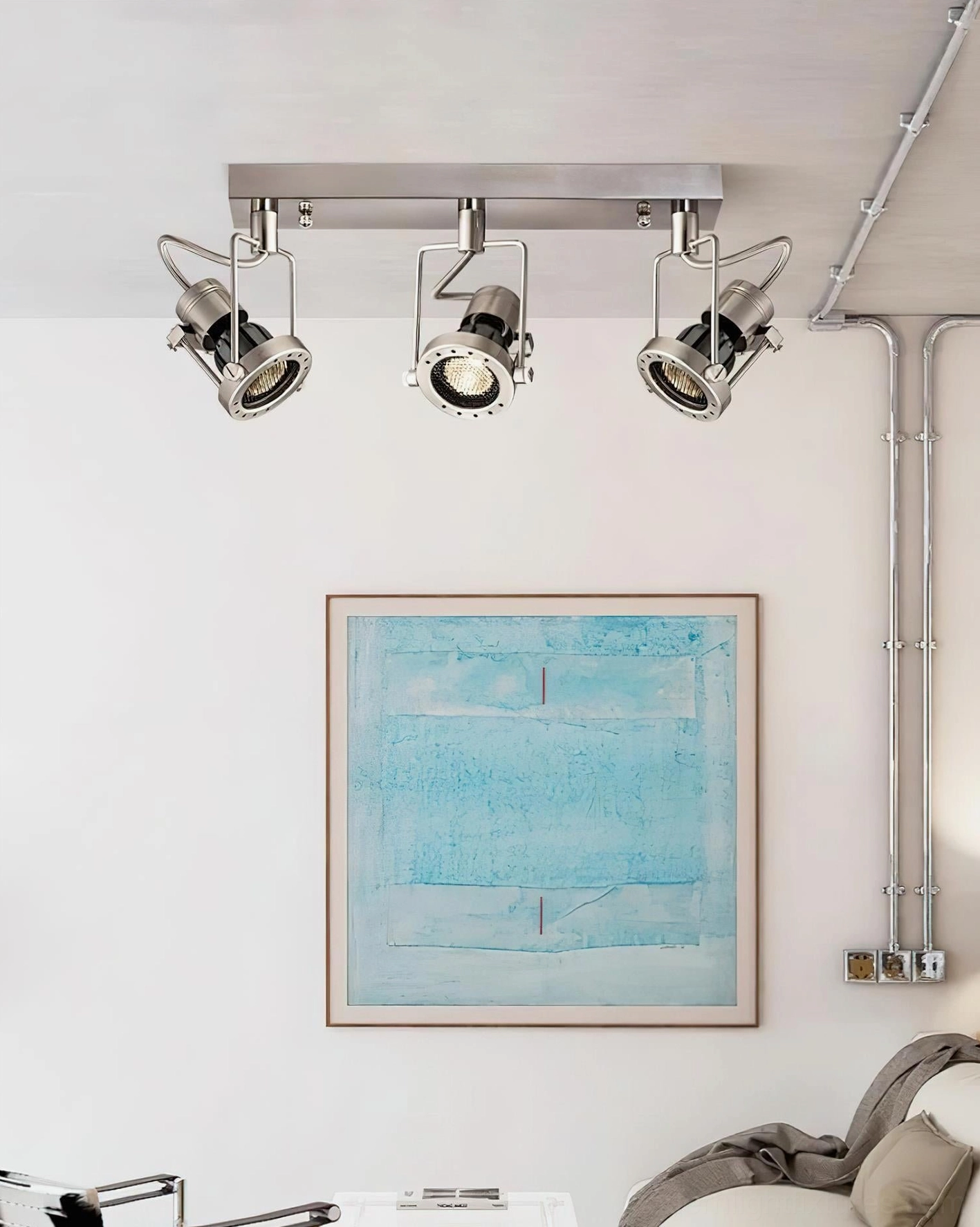 Modern minimalist living room with 3-head linear track lighting accentuating wall art and brushed silver finish