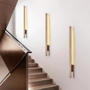 Vedra stone wall sconce installed in residential stairwell, warm lighting on wooden stairs, contemporary interior design