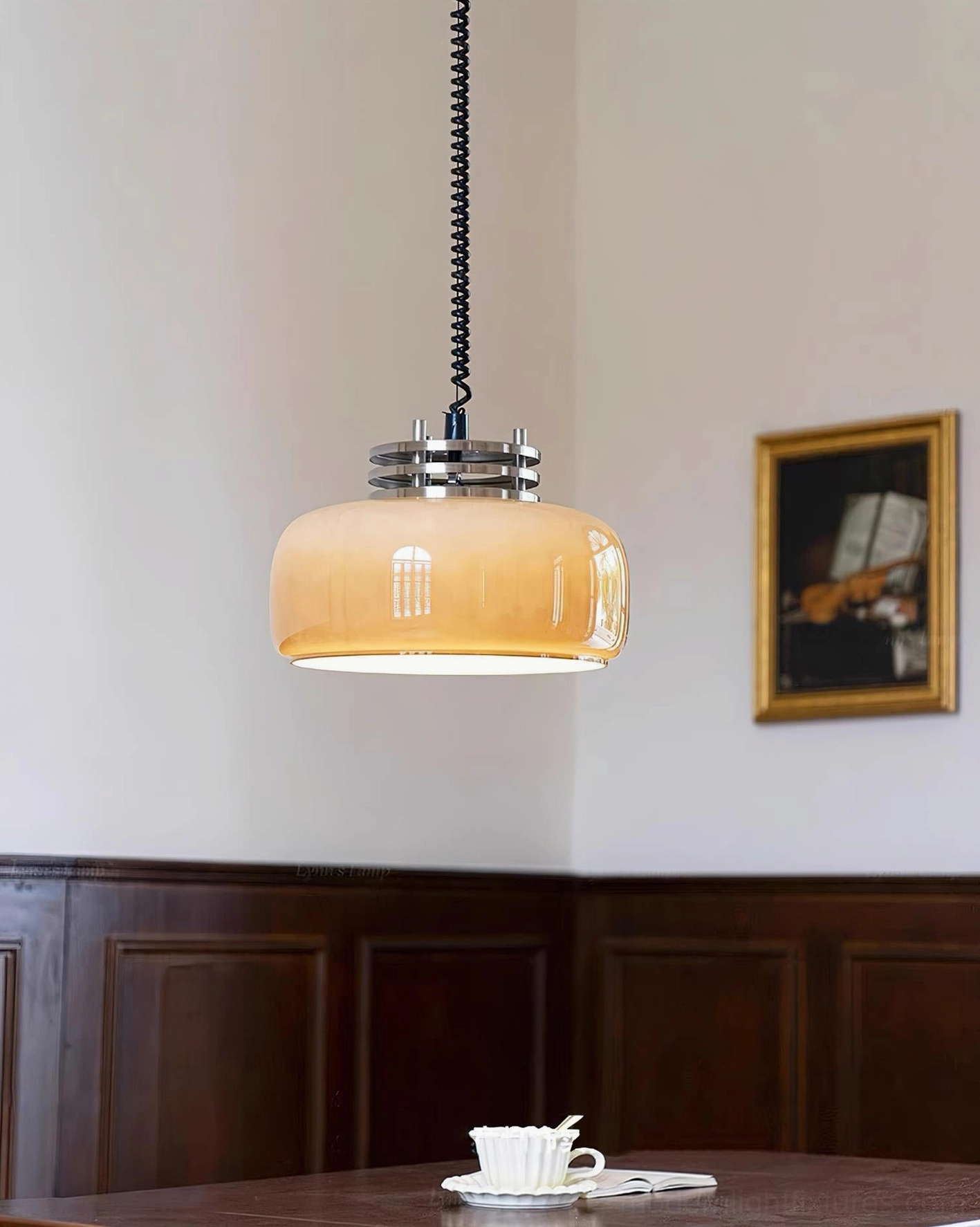 Warm glowing Vela pendant lamp above dining table in vintage room, three-quarter illuminated view