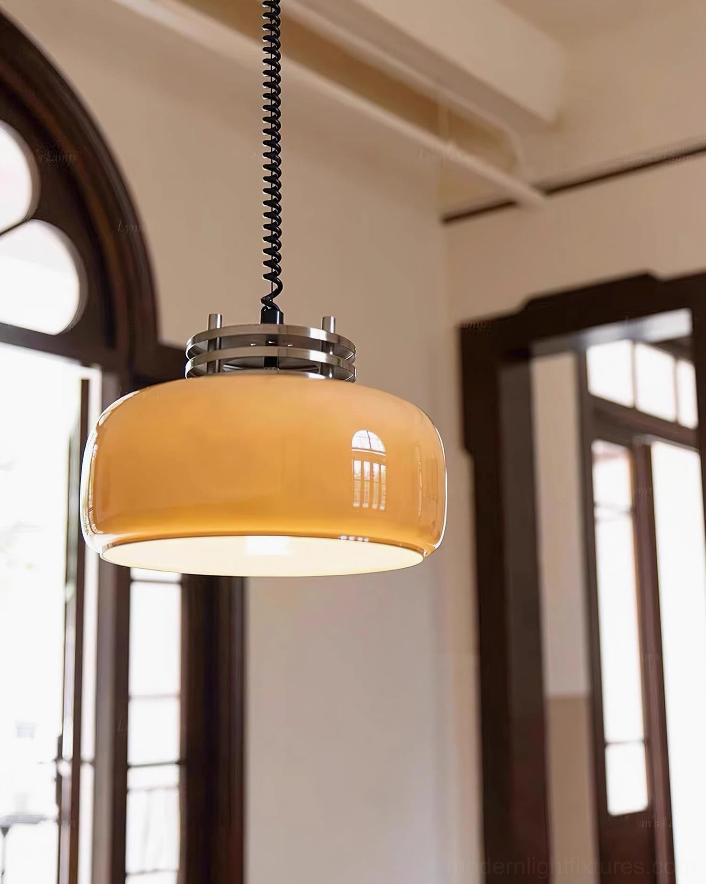 Lit Vela pendant lamp in vintage home with arched wood windows, three-quarter front perspective