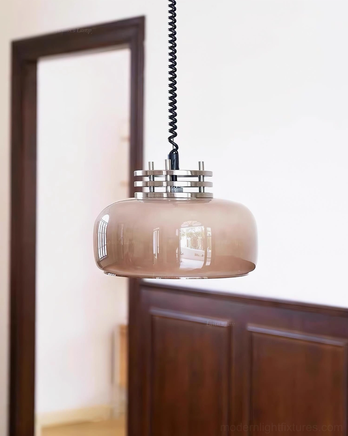 Brown Vela pendant light in dining room with dark wood paneling, three-quarter side view