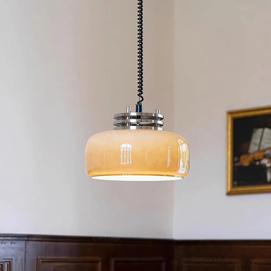 Illuminated Vela pendant light with warm amber glow in vintage dining room, close-up front view