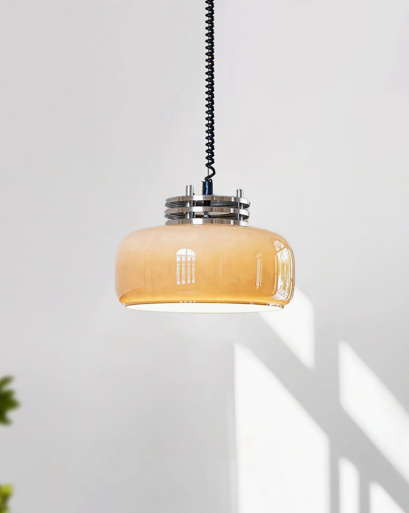 Illuminated Vela pendant light with amber glass shade and polished chrome hardware, studio flat view