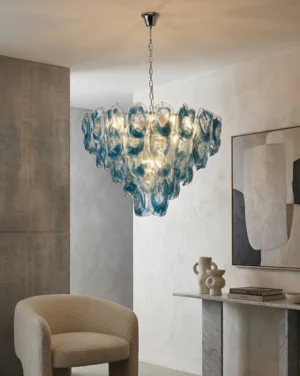 Blue swirl hand-formed glass chandelier installed in minimalist modern living area with upward angle showing layered glass design