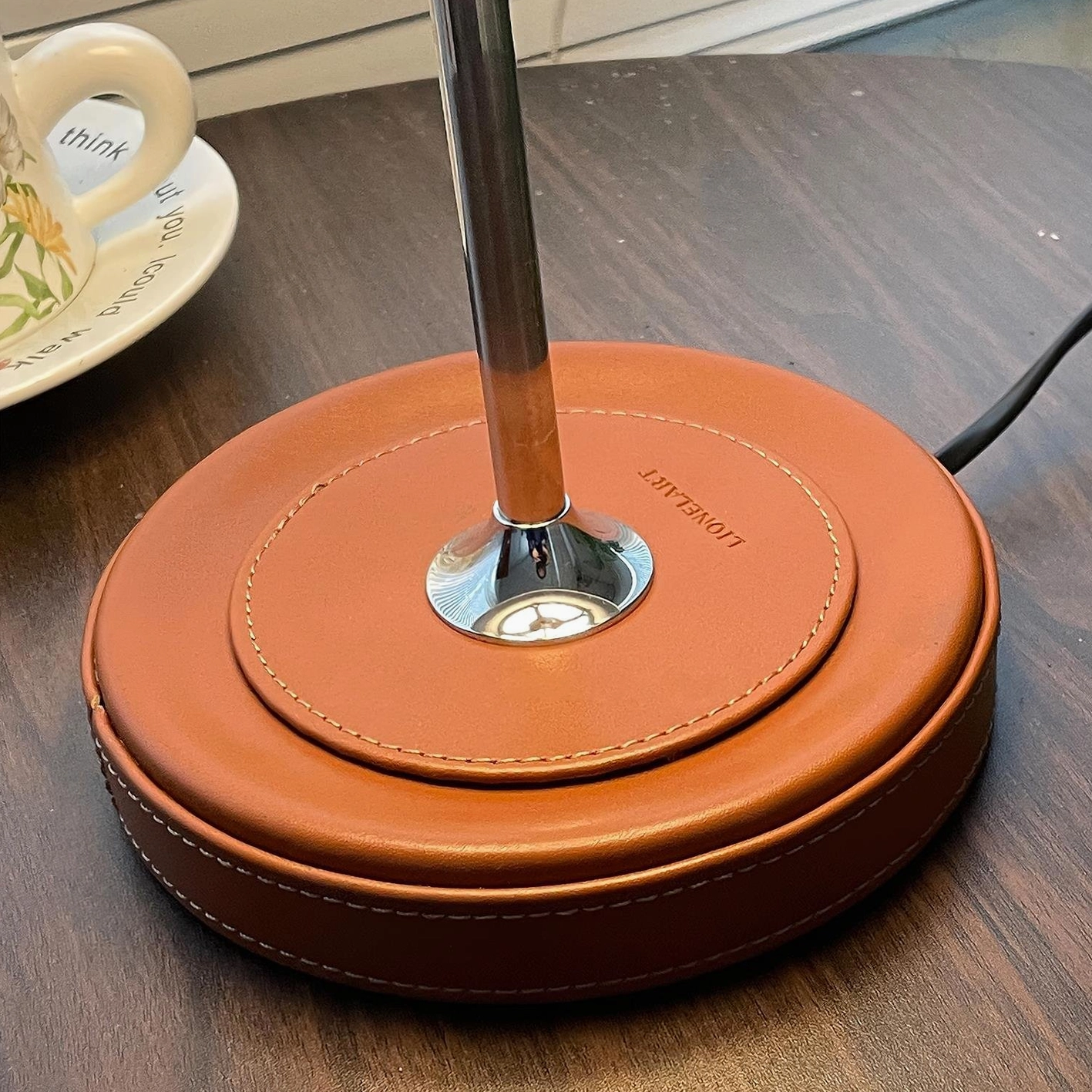 Veltrix table lamp leather base detail showing stitching and engraved branding on wooden surface
