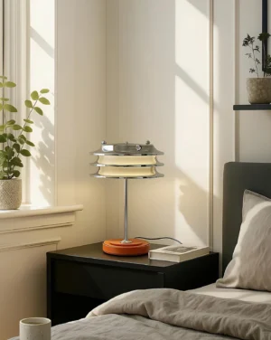 Contemporary tiered table lamp in bedroom setting on wooden nightstand with orange leather base